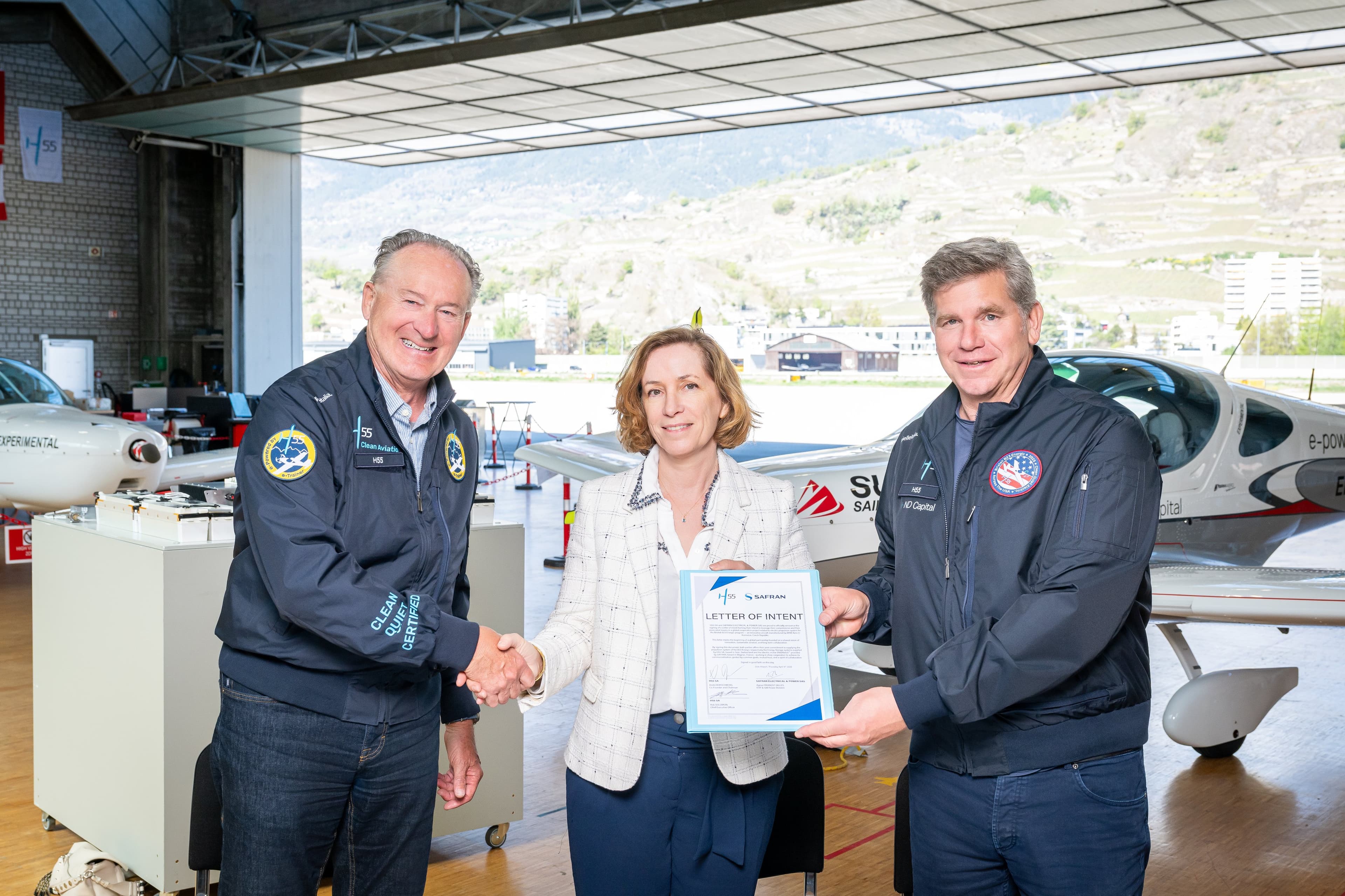 Poignée de main et lettre d’intention brandie par trois dirigeants, dans le hangar ouvert sur les vignes