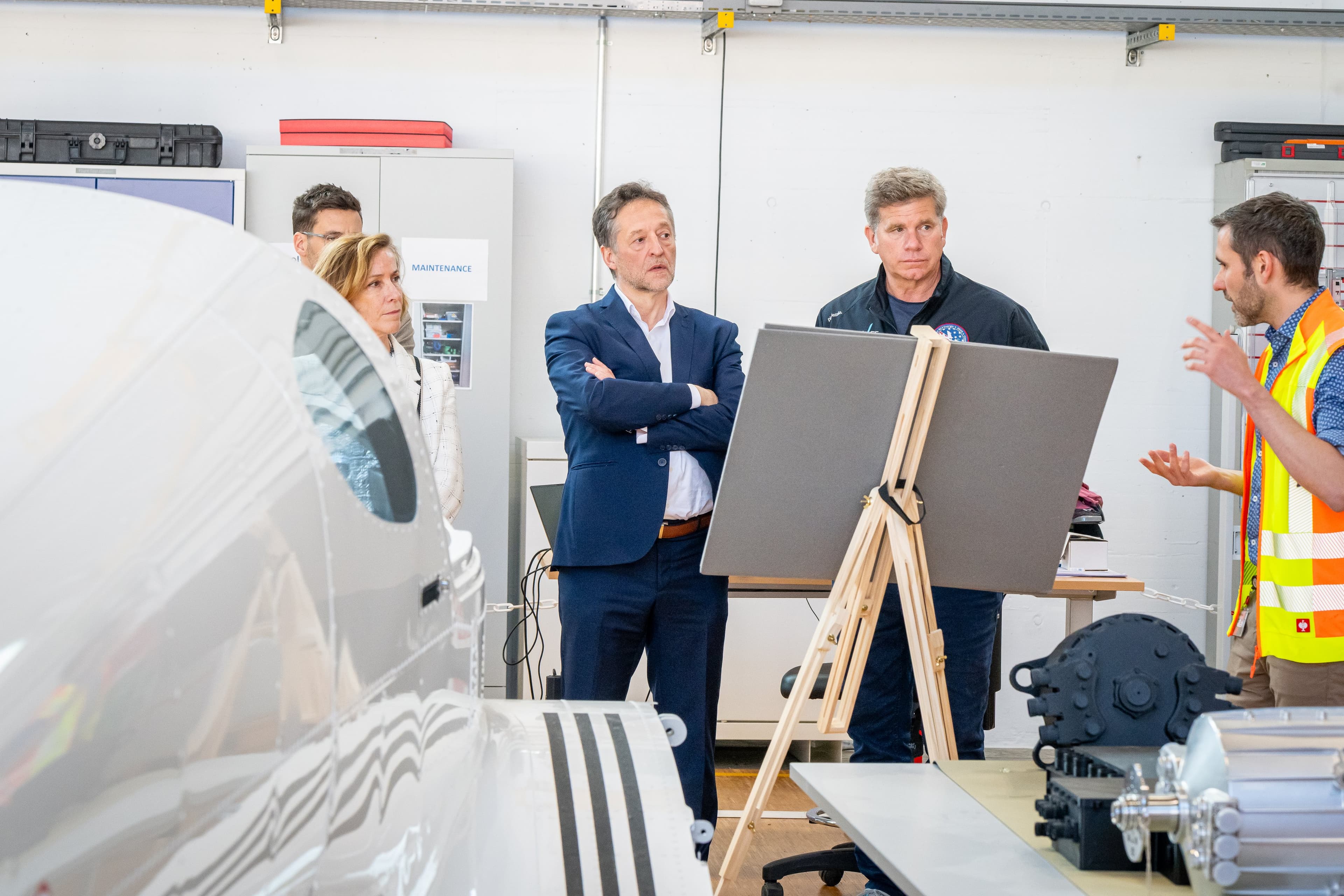 Présentation dans l’atelier H55 : un technicien explique, la délégation écoute, bras croisés