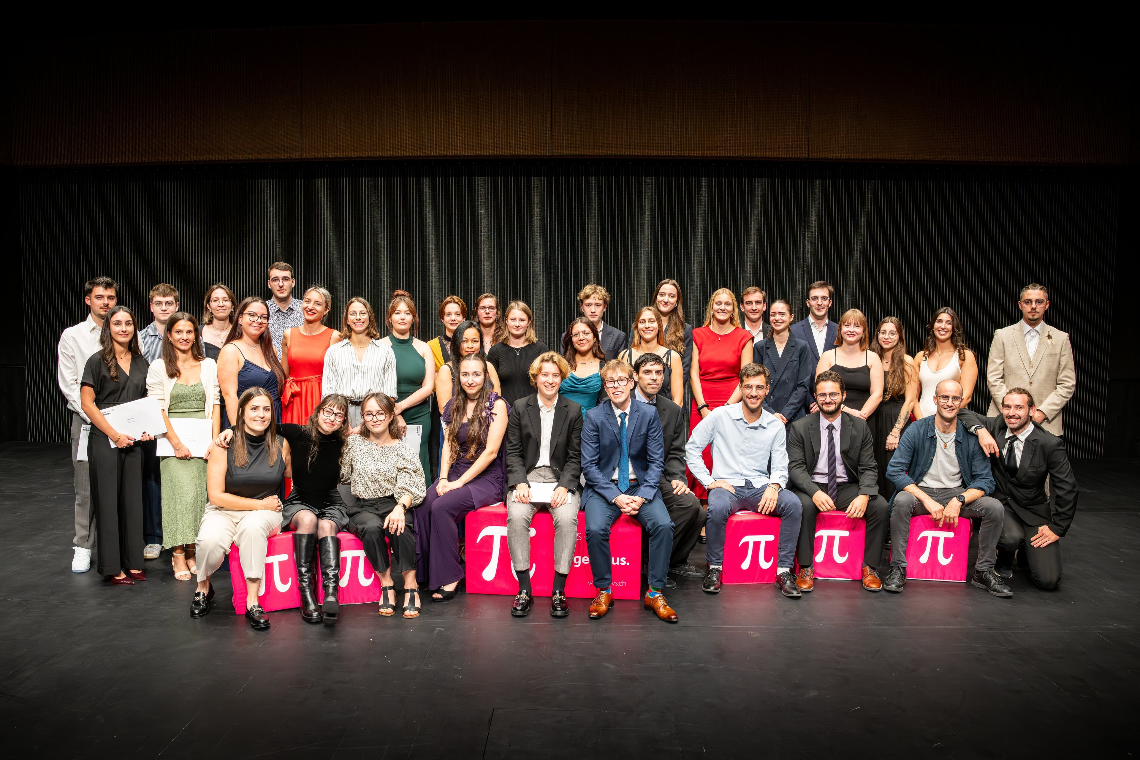 Les diplômés ingénieurs réunis sur la scène, assis et debout derrière des cubes roses marqués π